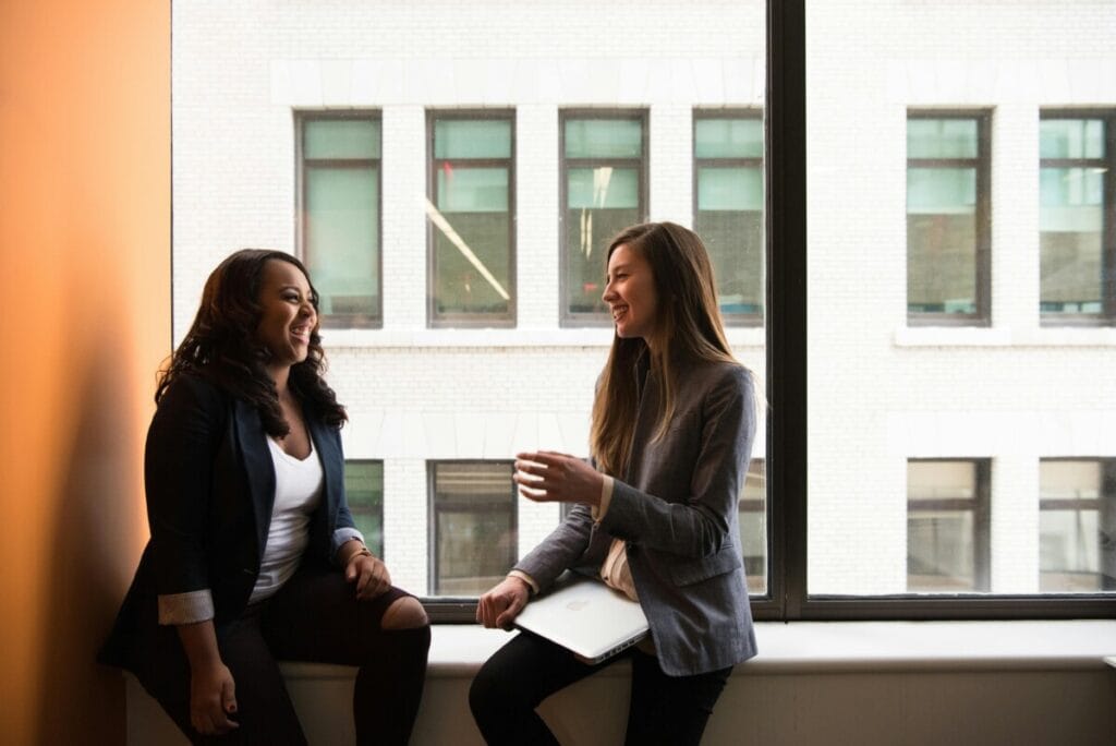 Two friends by a window, modeling open conversation and handling hurt in relationships