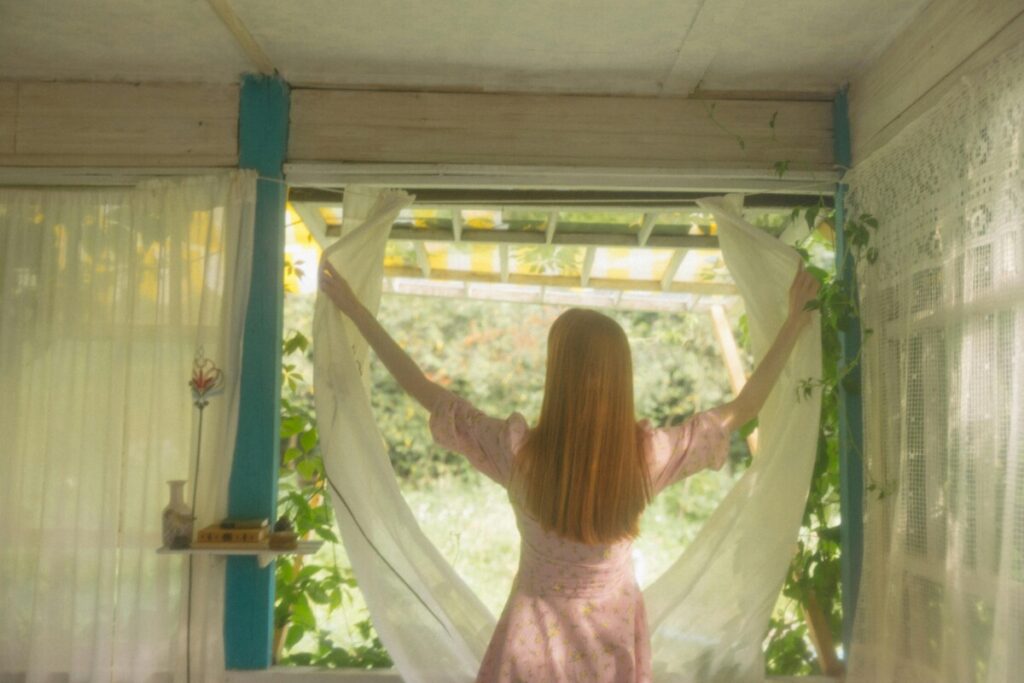 이 사진은 커튼을 젖히며 아침 햇살을 맞는 여성의 모습을 담고 있습니다.
5년 후 미래의 나에게 보내는 글에서 강조한 “아침 습관”을 시각적으로 보여주며, 하루를 새롭게 열고 자신을 돌보는 회복의 힘을 상징합니다.