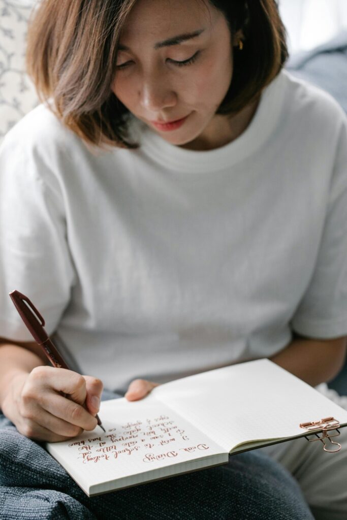 이 사진은 40대 여성이 노트에 글을 쓰며 하루를 성찰하는 모습을 담았습니다. Toronto 교실에서 배운 감정코칭 습관이 교실을 넘어 성인의 자기돌봄으로 확장되는 의미를 보여줍니다.”