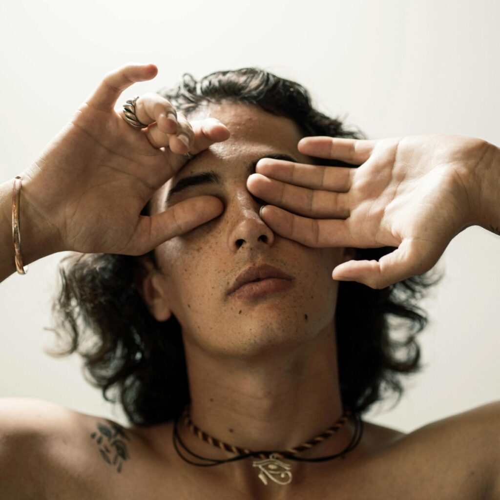 젊은 남성이 두 손으로 눈을 가리고 깊게 숨 쉬며 감정을 안정시키는 모습.-감정이 무뎌졌을 때 뇌를 쉬게 하는 호흡과 감정 정리의 상징적 장면입니다. 