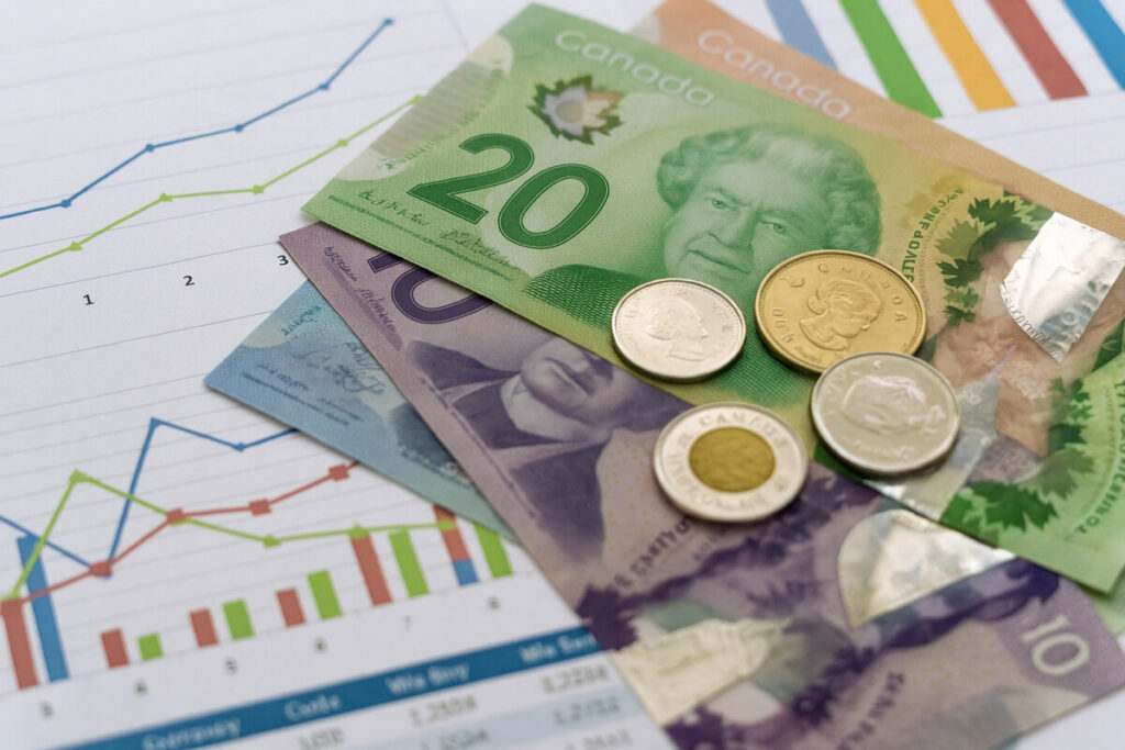 캐나다여행 환율 조회와 환전 전략을 설명하기 위해 재무 차트 위에 놓인 캐나다 달러와 동전.