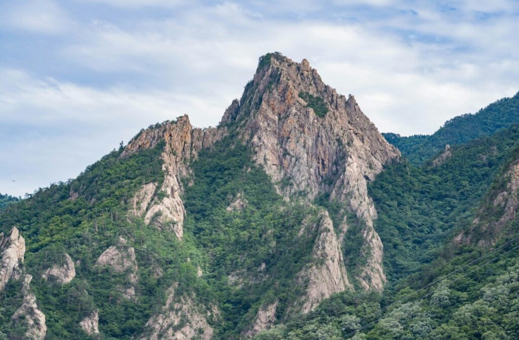 강원도 가볼만한곳 설악산 국립공원의 숨 막히는 비경을 보여주는, 권금성 정상의 웅장한 기암괴석들-드라마틱한 구름 낀 하늘을 배경으로 설악산의 날카롭고 울퉁불퉁한 화강암 봉우리들을 가까이에서 포착한 드라마틱한 풍경입니다. 강원도의 중심 명소인 설악산의 원시적인 자연미와 영적인 힘을 잘 담아내고 있습니다.