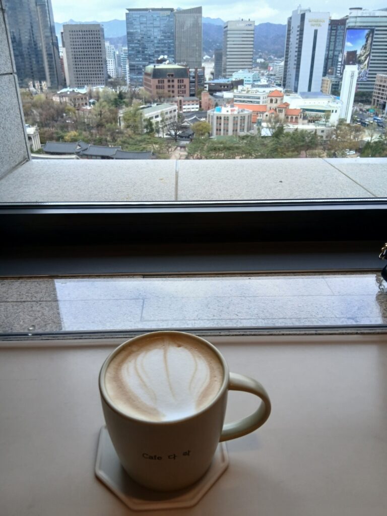 정동전망대 카페 다락 창가 자리에 놓인 따뜻한 카페라떼 한 잔과 창밖 덕수궁 풍경-캐나다 선배와 도란도란 이야기를 나누며 정동전망대 덕수궁 산책을 행복하게 마무리한 공간입니다.