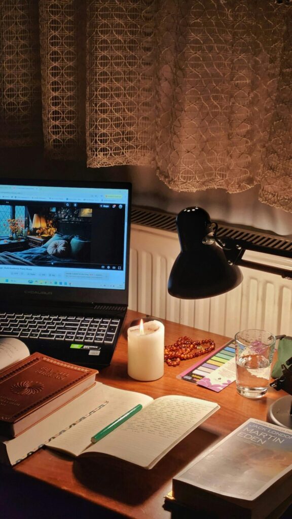 따뜻한 촛불 조명 아래 노트북과 노트가 놓인 예술인의 작업 책상-예술활동지원금 신청