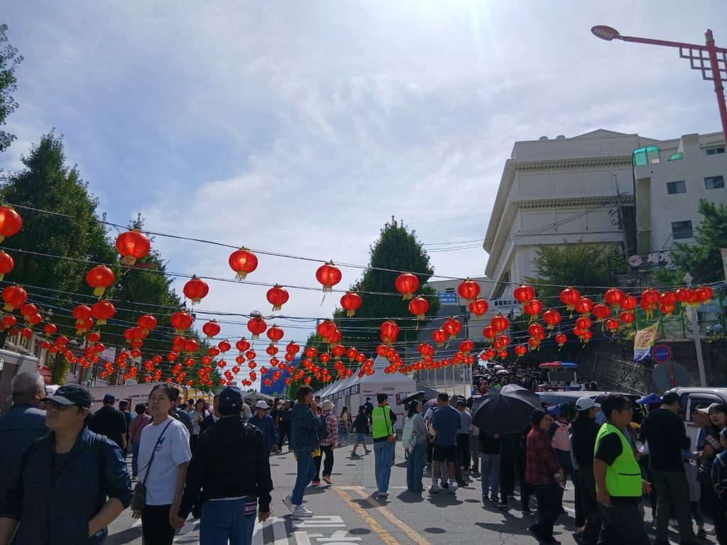 인천 짜장면 축제 차이나타운 입구 패루와 붉은 홍등 거리 인파-인천 짜장면 축제를 즐기기 위해 전국에서 모여든 수많은 방문객과 활기찬 차이나타운 거리의 전경입니다.